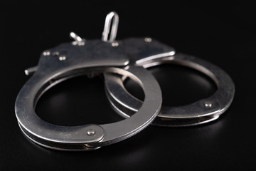 Nickel-plated handcuffs on a black table. Accessories for special services and police.