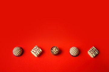 St. Valentine's Day. Chocolate candies on a red background. Candies in one line. Chocolate treats....