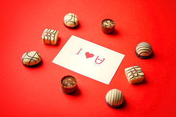 St. Valentine's Day. Chocolate candies on a red background. Candies in one line. Chocolate treats....
