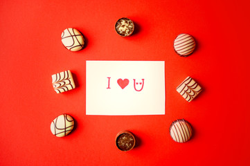 St. Valentine's Day. Chocolate candies on a red background. Candies in one line. Chocolate treats. Assorted chocolates.