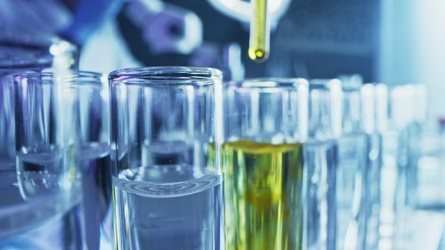 Pharmaceutics Laboratory: Pipette Dropping Yellow Liquid into Test Tubes, Medical Research, Analysis. Scientific Lab; Dropper Fills Sample Tubes with Innovative DNA Study Solution. Close-up Macro