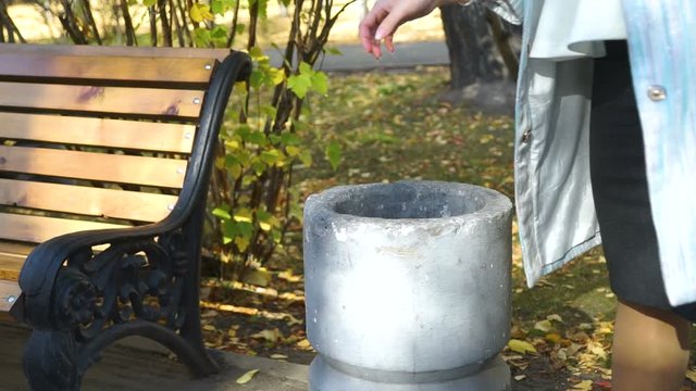 Young Woman Throws Trush in the Trash Bin
