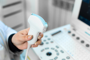 Doctor prepare an ultrasound machine for the diagnosis of a patient. Doctor puts media gel on an...