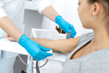 A nurse inserts a needle into a vein on a patient arm. Blood sampling procedure