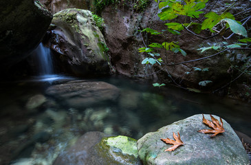Fototapeta premium Idyllic calm lake with blue clean water and small waterfall flowing between the rocks.