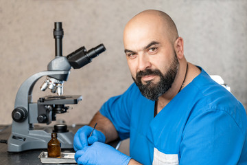 Male laboratory assistant examining biomaterial samples in a microscope