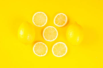 Lemons on bright yellow background. Lemon background concept, flat lay. Lemon fruit, citrus minimal concept. Creative background made of lemon and leaf. Top View.