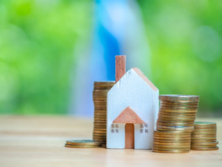 House or Home model and a container for saving money on near of coins stack. Concept for loan, property ladder, financial, mortgage, real estate investment, taxes and bonus.
