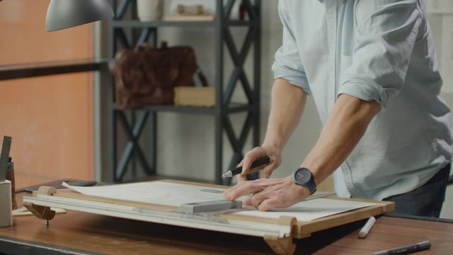 Architect man sits at drafting table in modern industrial office during the day