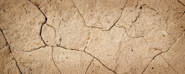 Concrete wall texture with cracked plaster. Weathered uneven rough surface. Perfect background for header, website and grunge design.