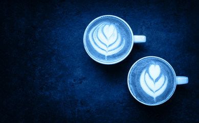 Two cups of blue matcha on black rustic background with beautiful latte art