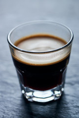 Coffee in glass cup on dark stone background. Close up. 