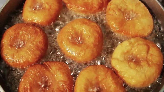 Doughnuts are fried in oil in a frying pan closeup
