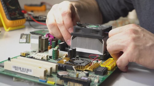 Electronic technician disassembles the motherboard for cleaning. PC repair. Removes the processor from the Board