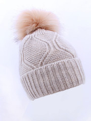 Fototapeta na wymiar Beige Wool Knit Ski Hat with Faux Fur Pompom Isolated on White. Bobble Hat Topped with Pom Pom or Loose Tassels. Knit Cap Folded Brim. Knitted Warm Hat. Tuque or Toque Outdoors Headgear