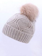 Beige Wool Knit Ski Hat with Faux Fur Pompom Isolated on White. Bobble Hat Topped with Pom Pom or Loose Tassels. Knit Cap Folded Brim. Knitted Warm Hat. Tuque or Toque Outdoors Headgear