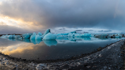 Sunset reflection over lagoon with icebergs os deep blue ice at Iceland Jokulsarlon glacier lagoon