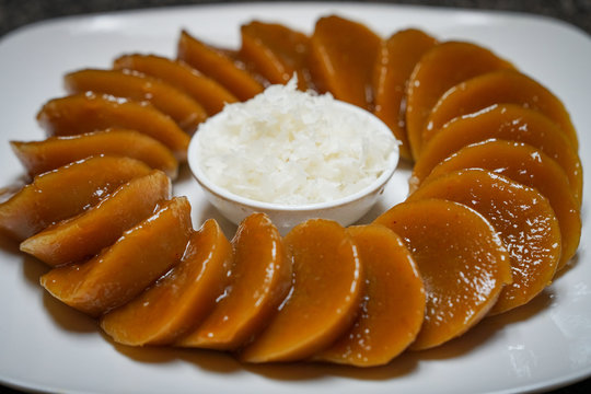 Closeup view of homemade Filipino dish Kutsinta with coconut flakes on a white plate
