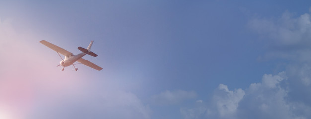Lonely small plane on a background of blue sky and clouds, panoramic view.