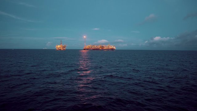 FPSO tanker vessel near Oil Rig platform. Offshore oil and gas industry. Flare is burning with smoke. View from supply vessel.
