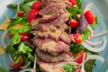 Lomo saltado in lettuce bed with saturated colors on blue plate