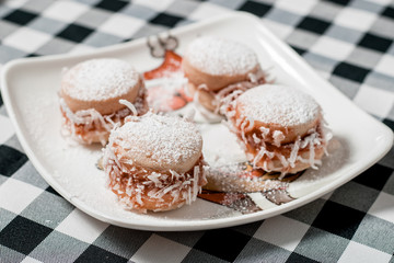 4 Latin American alfajores with arequipe and coconut on plaid background
