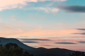Fototapeta na wymiar sunset sky over the hills in Tasmania, Australia with soft tones and trees