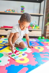 Fototapeta premium Beautiful african american toddler playing with maths game using numbers at kindergarten