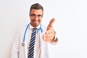 Young handsome doctor man wearing stethoscope over isolated background smiling friendly offering handshake as greeting and welcoming. Successful business.