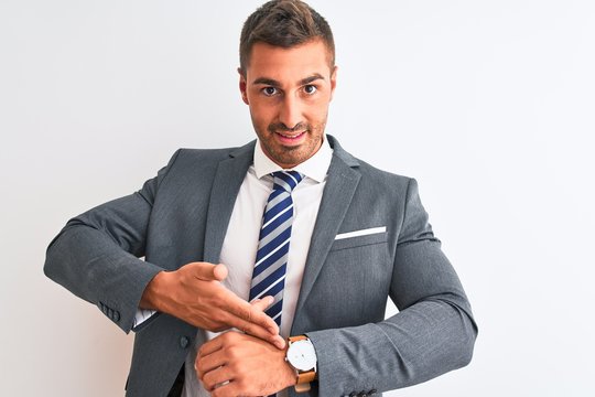 Young handsome business man wearing suit and tie over isolated background In hurry pointing to watch time, impatience, upset and angry for deadline delay