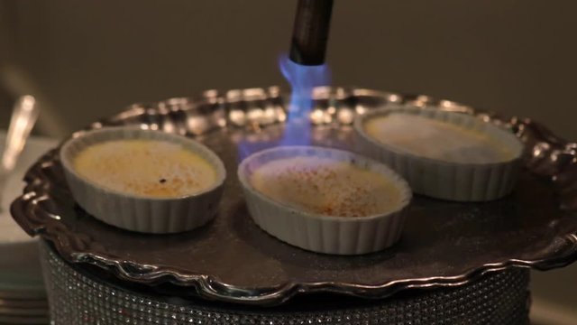 Mini creme brulee being toated with flame close