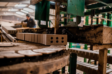 Plant for the production of bricks from clay. Plant for production building material with ready brick, construction industrial. Production of bricks on plant. Workflow, close-up. Many raw bricks