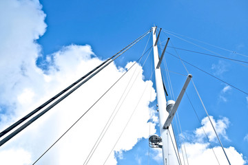Furled fore sails and tall white mast of a modern maxi sailing yacht.