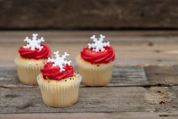 Winter cupcakes with red icing and a snow flake on a wooden background 