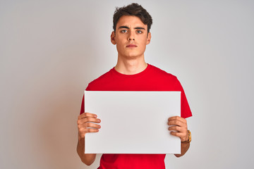 Teenager boy holding advertising banner with blank space over isolated background with a confident...