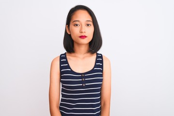 Young chinese woman wearing striped t-shirt standing over isolated white background Relaxed with serious expression on face. Simple and natural looking at the camera.