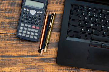 scientific calculator, pencil, laptop and pen on the table