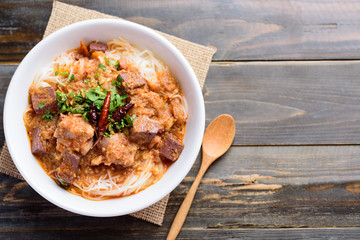 Northern Thai food (Kanom Jeen Nam Ngeaw), rice noodles with spicy soup in bowl on wooden background