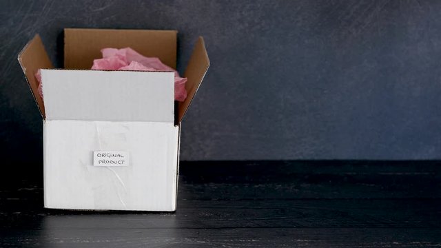 original product vs dupe imitation label on delivery parcel boxes from online purchases and hand taking away the imitation item leaving only the original one in the centre of the frame