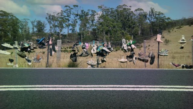Sneakers hanging on a fence by the road