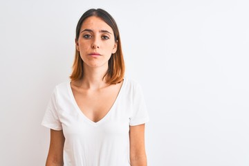 Fototapeta premium Beautiful redhead woman wearing casual white t-shirt over isolated background Relaxed with serious expression on face. Simple and natural looking at the camera.