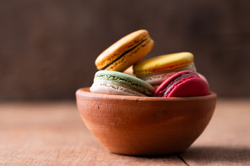 Pile of sweet and colourful french macaroons on wood background.