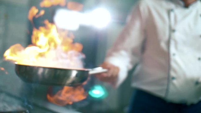 Preparing a meal - Chef cooks meat on an open fire in the kitchen on the stove in the pan
