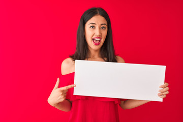 Young beautiful chinese woman holding banner standing over isolated red background very happy pointing with hand and finger