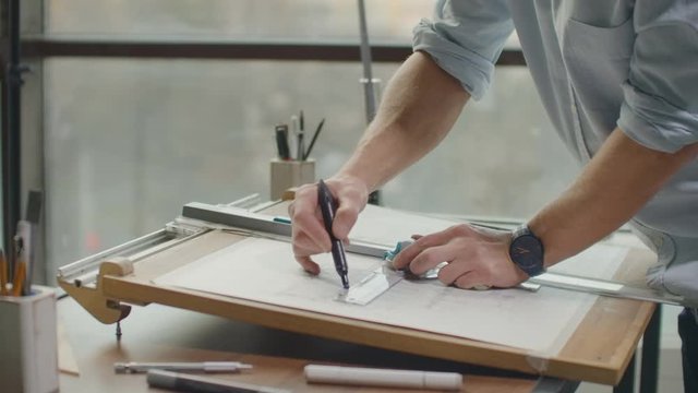 Close up of architect hands making house blueprint in the office near window. Concept: architecture, blueprint house, paper work.