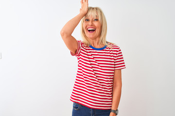 Middle age woman wearing casual striped t-shirt standing over isolated white background surprised...
