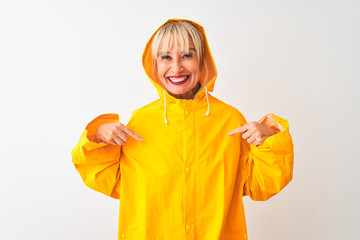 Middle age woman wearing rain coat with hood standing over isolated white background looking confident with smile on face, pointing oneself with fingers proud and happy.