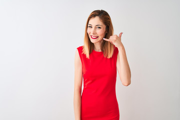 Redhead businesswoman wearing elegant red dress standing over isolated white background smiling doing phone gesture with hand and fingers like talking on the telephone. Communicating concepts.