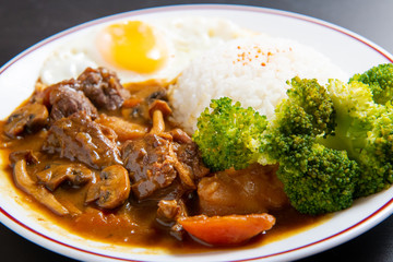 beef Curry Rice on black wooden background ( Onsen tamago, Potato, enoki mushroom, onion, broccoli, Japanese style)