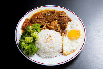 beef Curry Rice on black wooden background ( Onsen tamago, Potato, enoki mushroom, onion, broccoli, Japanese style)